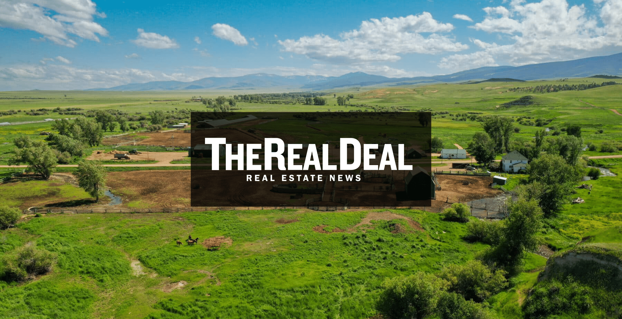 A green rural landscape with scattered trees, farm buildings, and mountains in the background suggests prime land for sale. Overlaid in the center is a black rectangle with white text reading The Real Deal - Real Estate News.
