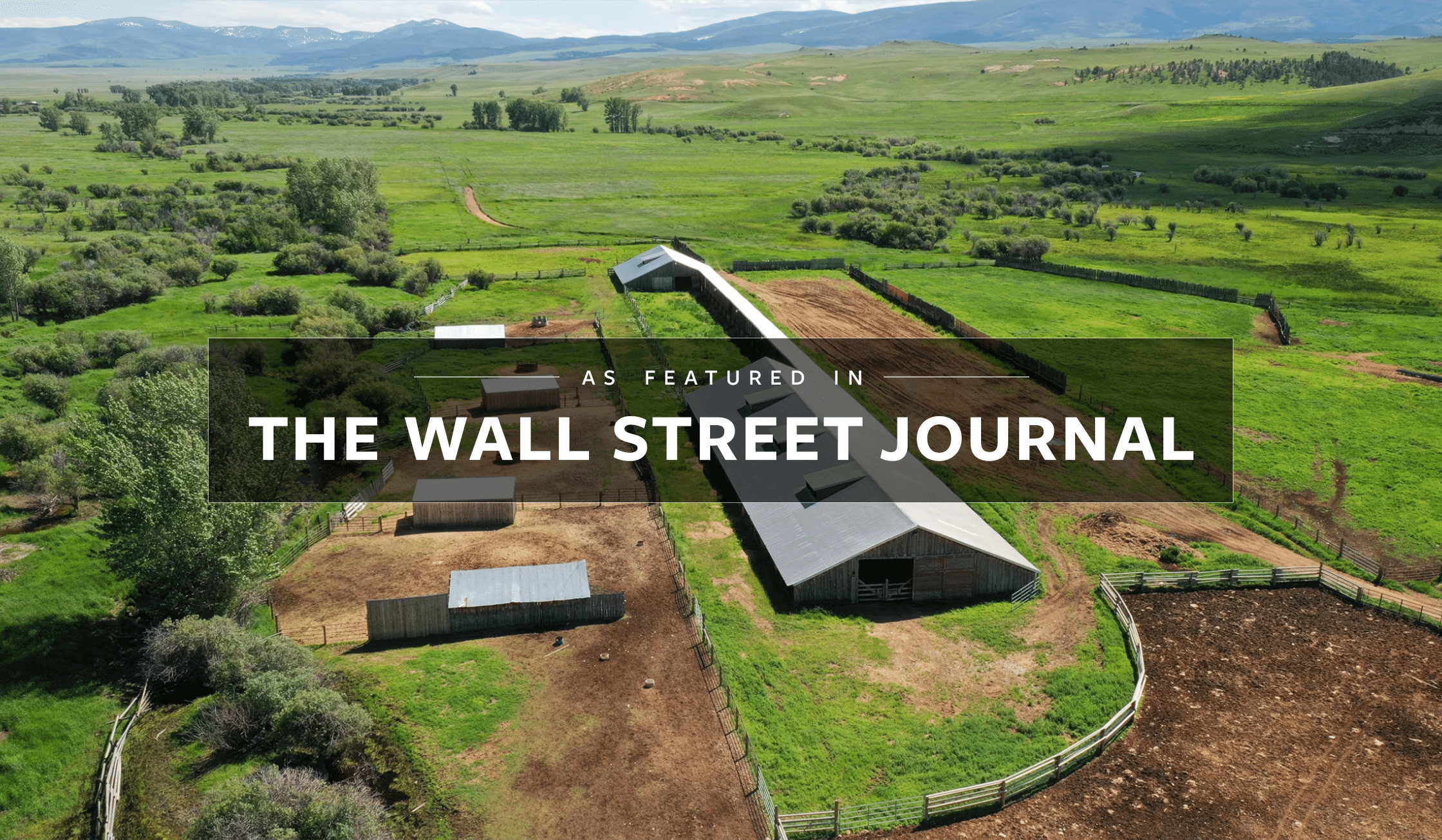 Aerial view of a large ranch for sale with barns and fenced areas, surrounded by green fields and rolling hills. Overlay text reads: As Featured In The Wall Street Journal.